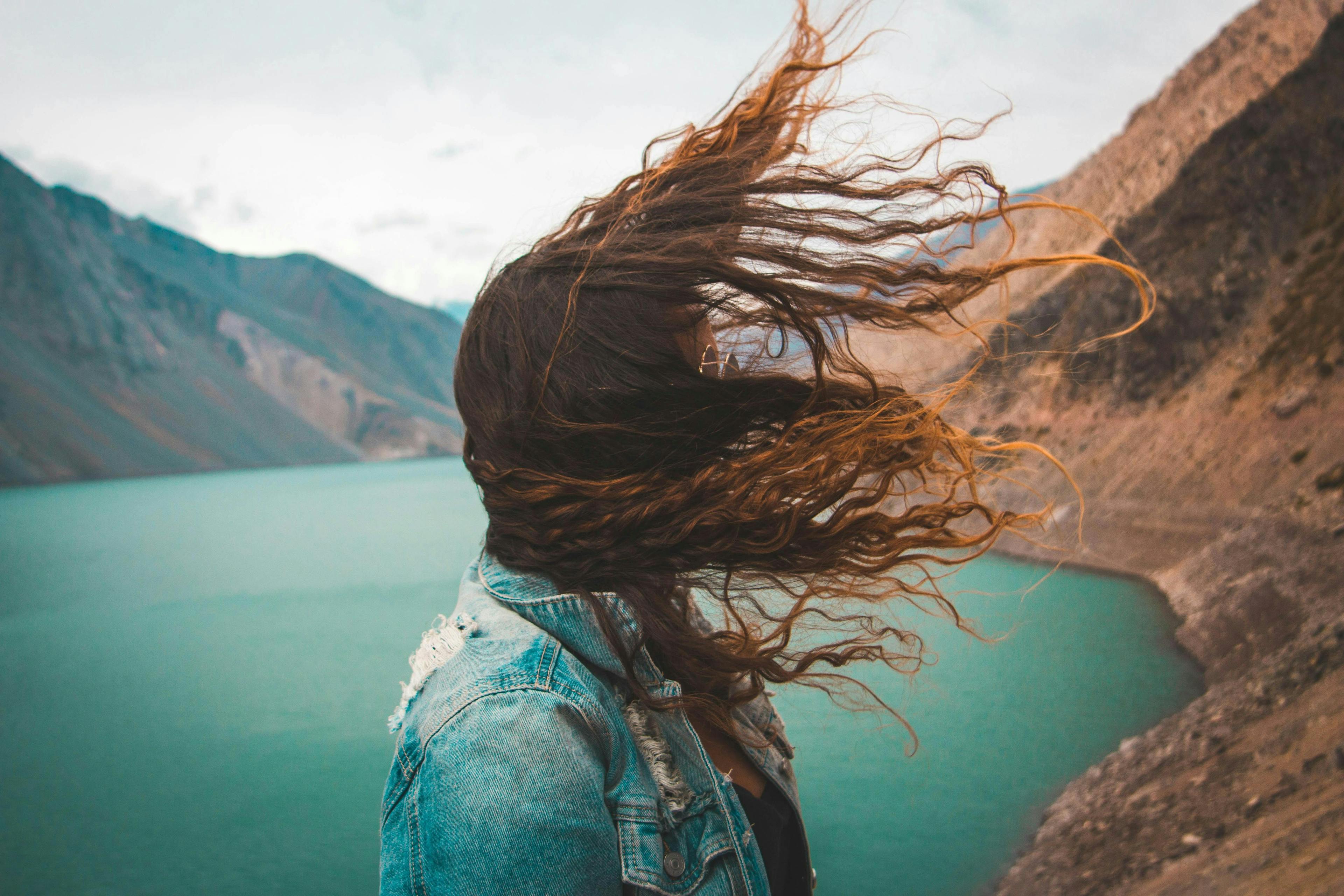 Woman looking at lake with hair blowing in the wind
